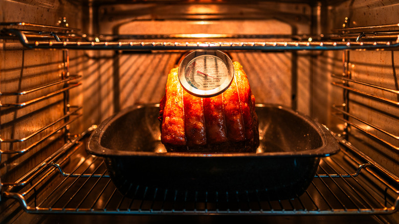 Prime rib roast in oven with thermometer inserted.