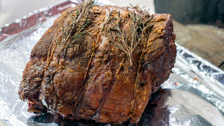 Prime rib roast with herbs resting on foil-lined sheet pan.
