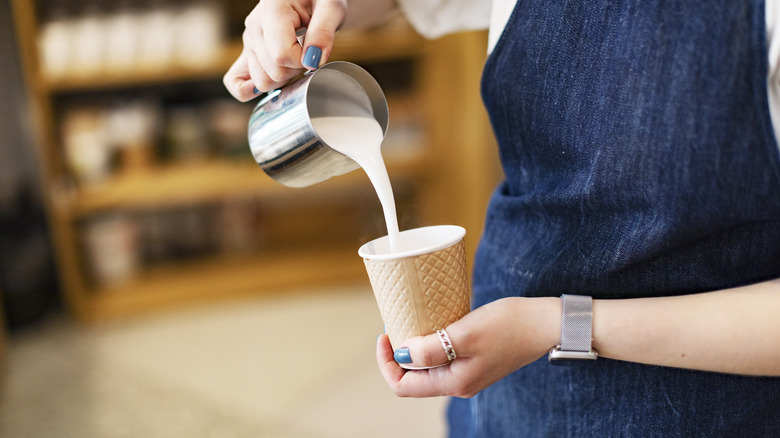 barista pouring milk in cup