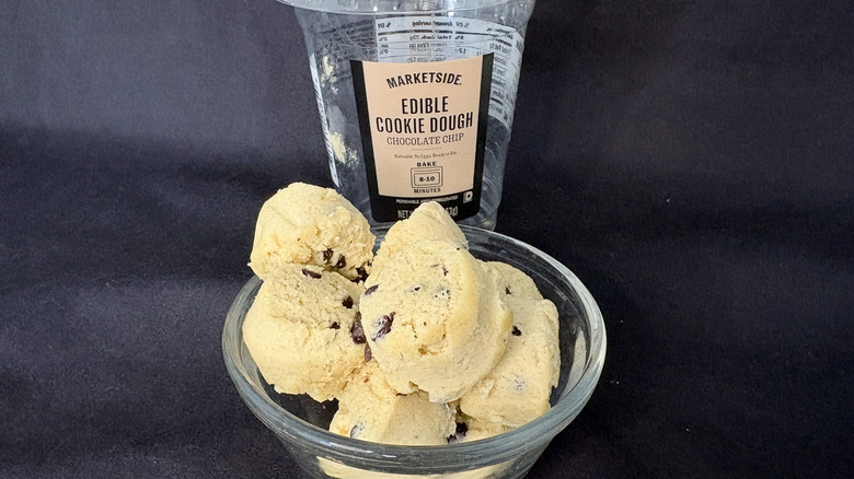 Scoops of edible cookie dough in a glass bowl with an empty package of Marketside Edible Cookie Dough behind