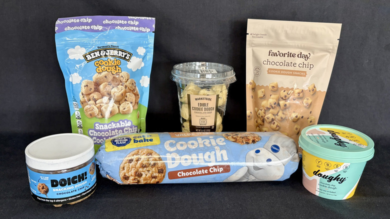 Six packages of edible chocolate chip cookie dough from different brands against a dark background