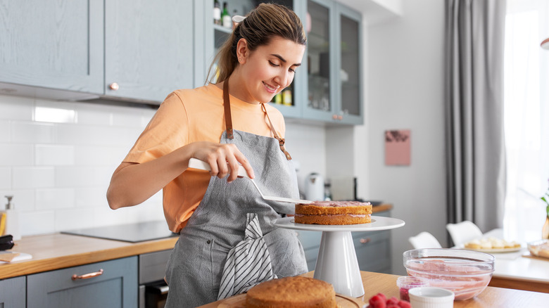 baker adding frosting to cake