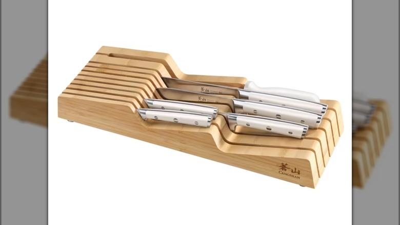 Wooden horizontal knife rack holding several kitchen knives.