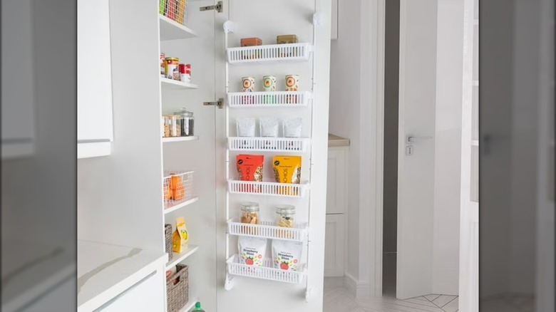 Pantry with hanging food rack attached to inside of open door.