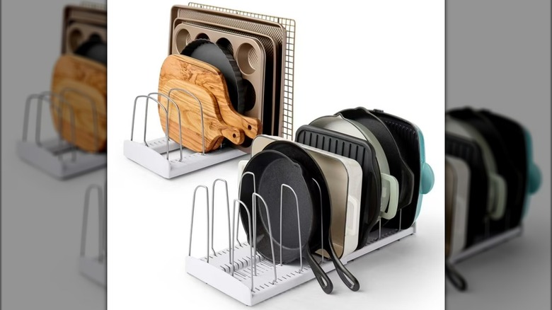 Two stand-alone cookware racks holding pans, cutting boards, and similar items.