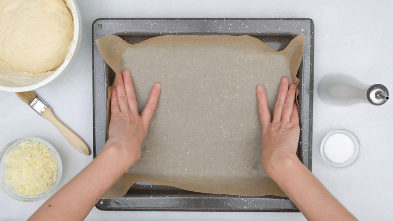 chef lining baking pan with parchment paper