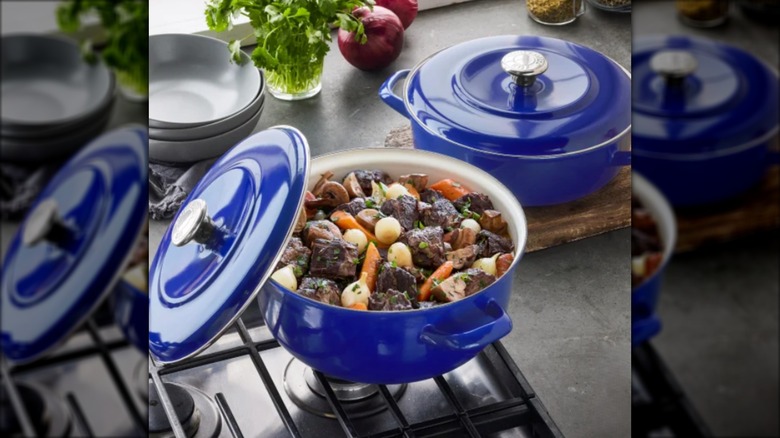 Blue cast iron Dutch oven on stove top with meat and vegetables