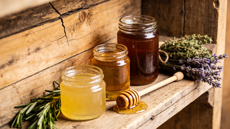 Three jars of honey on a rustic wooden table