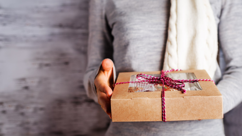 Unseen person holding box of home baked goods