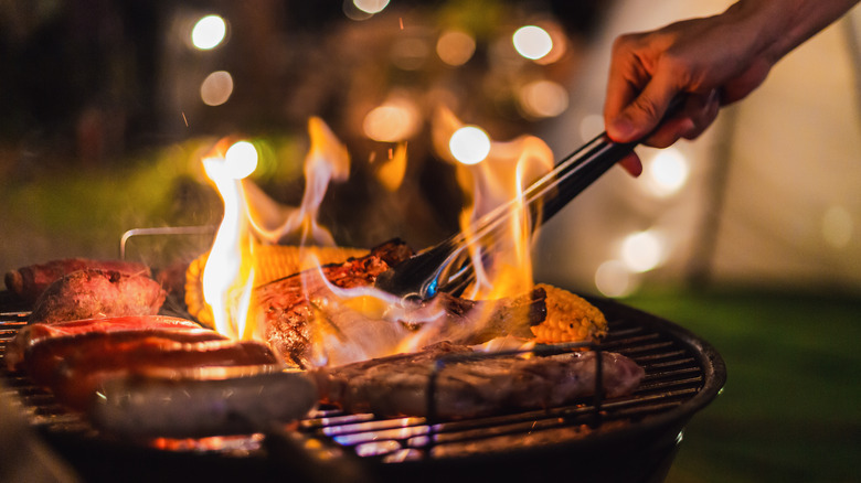 Grill with flames and cooking meats 