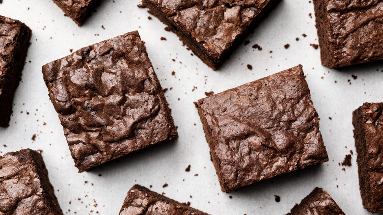 Square brownies on white background with crumbs