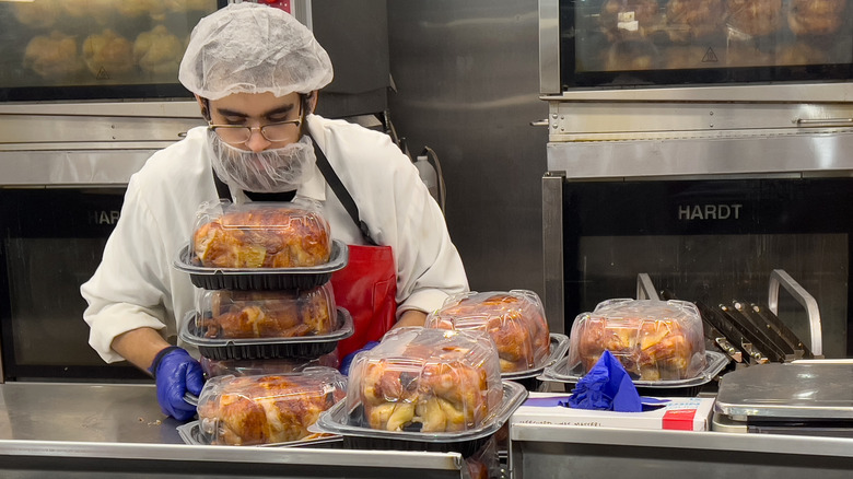 a Costco employee preparing rotisserie chickens