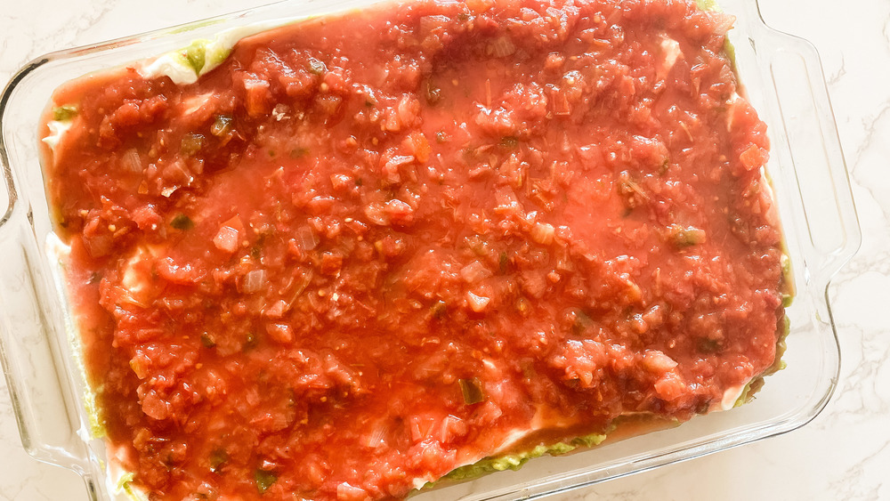 laag salsa in ovenschaal voor 7-laagse dip