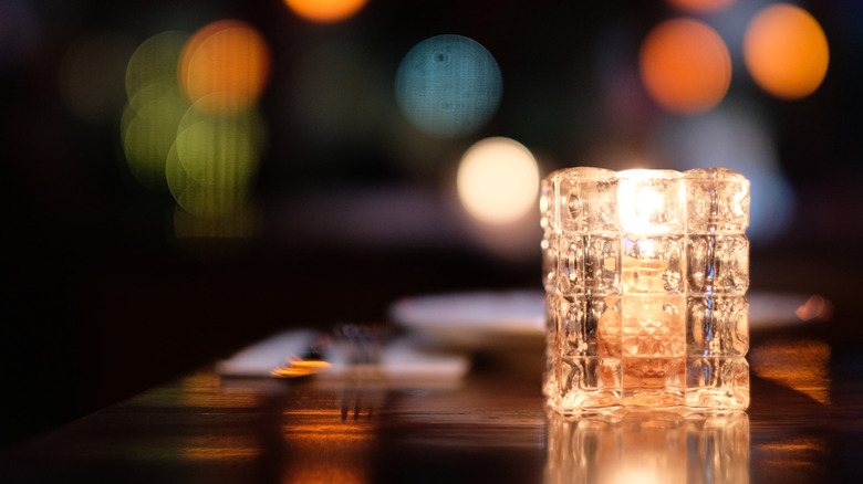 A lit candle in a glass holder at a restaurant