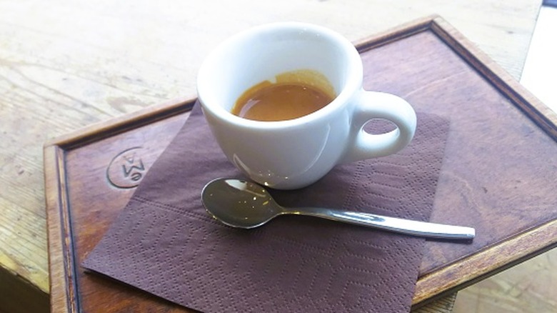 A white espresso cup with a spoon on a tray