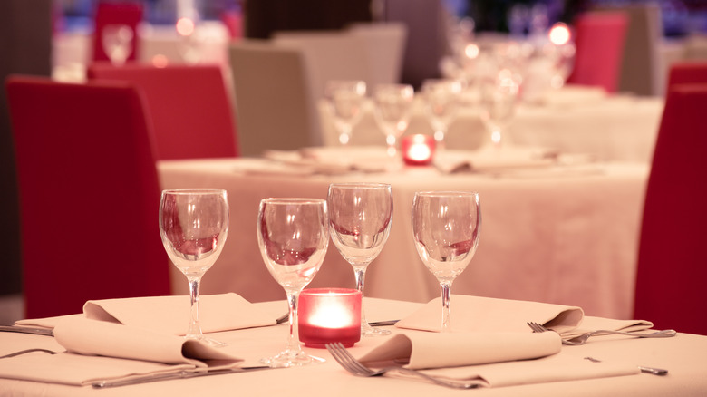 Restaurant tables set with glassware, candles, linen napkins, and cutlery