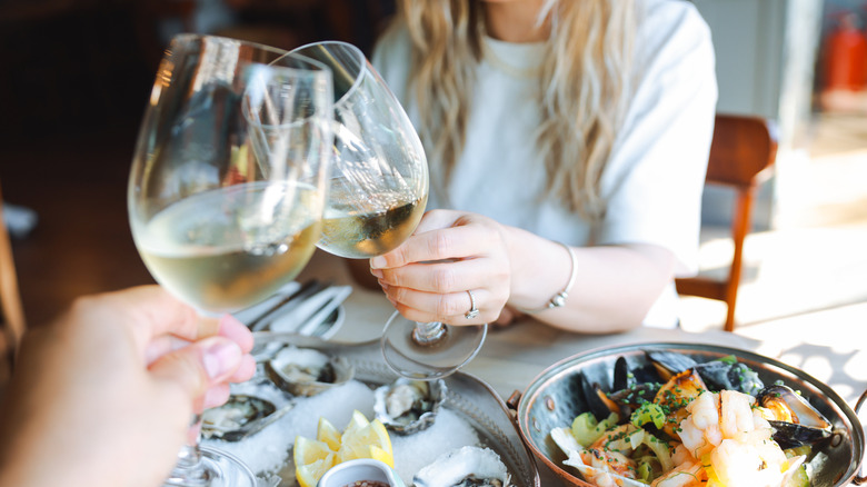 Two people clinking wine glasses at a restaurant table