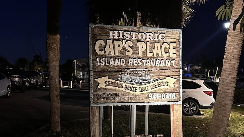 A historic sign for Cap's Place at night