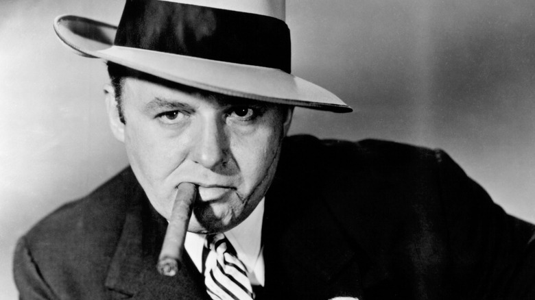 A classic black-and-white photo of Al Capone in a hat smoking a cigar