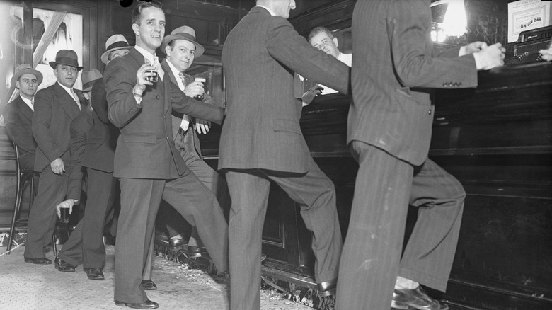 Black-and-white image of men in suits drinking at a bar during prohibition