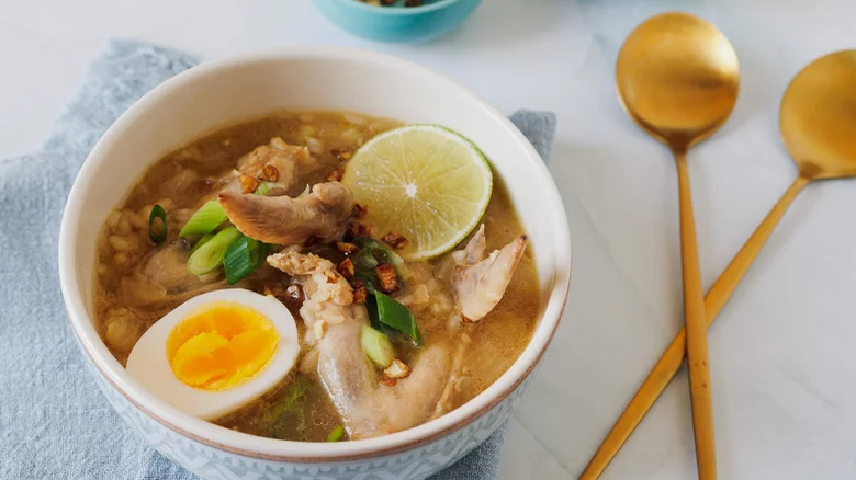 bowl of Chicken Arroz Caldo With Jammy Eggs and spoons