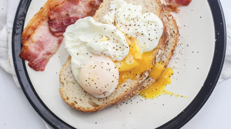 plate with poached eggs on toast with bacon