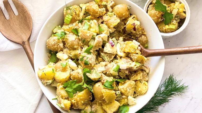 bowls of deviled egg potato salad and wooden utensils