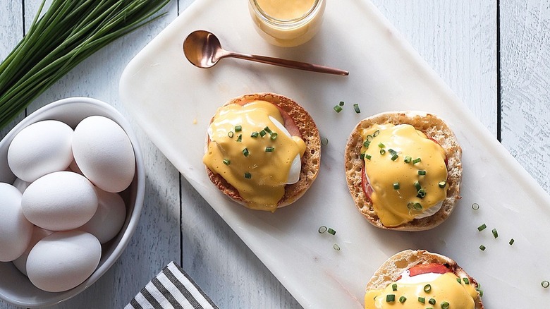 eggs benedict on plate with whole eggs on side