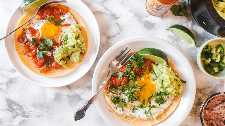plates of huevos rancheros with lime wedges and forks