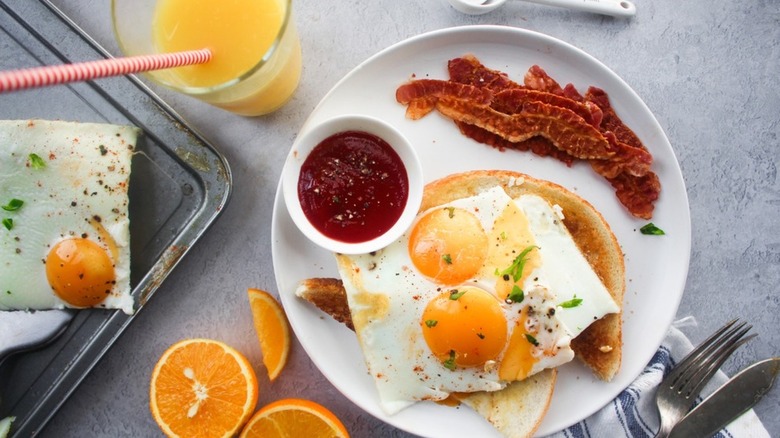 plate with sheet pan fried egg bacon toast jam orange juice
