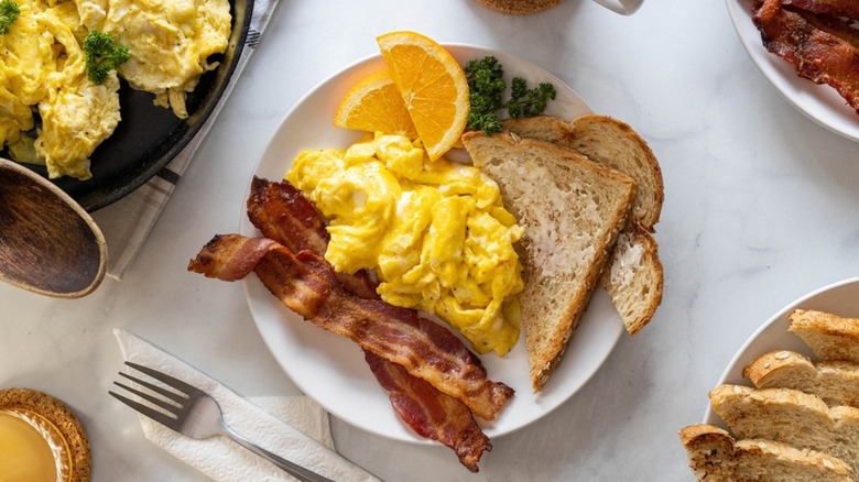 plate of scrambled eggs with toast and bacon