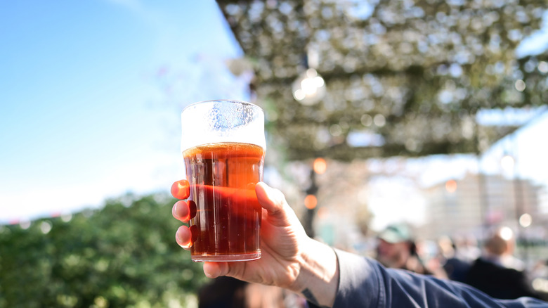 Hand holding a pint of beer on an outdoor patio