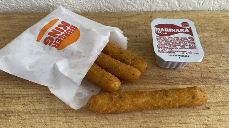 small bag of Burger King Mozzarella Fries beside marinara sauce cup