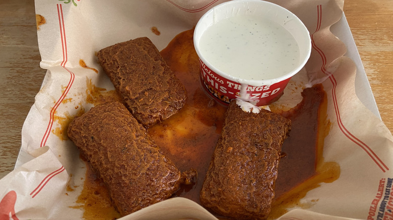 Chili's Nashville Hot Mozzarella, drenched in sauce with a bit of ranch spilling on one from an enormous container