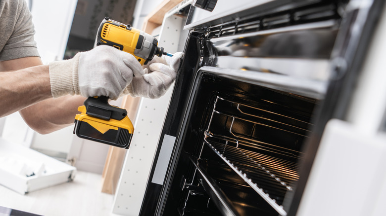 Person with a drill installing a gas stove