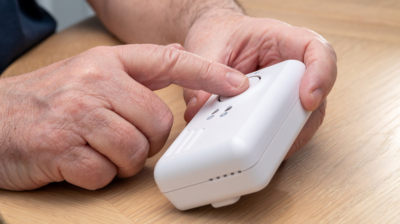 Person's hands checking a carbon monoxide detector