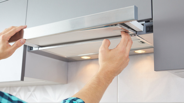 Hands removing one of the filters from the oven vent