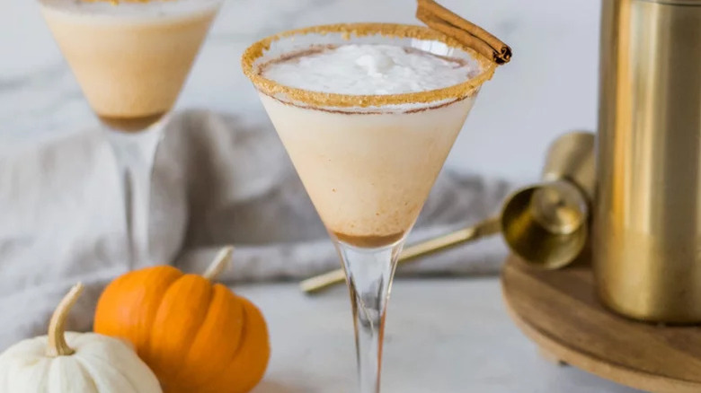 Creamy martini in a narrow martini glass with a spiced rim and cinnamon stick garnish.