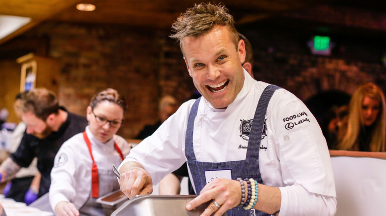 Chef Brian Malarkey working in a TV kitchen and grinning at the camera