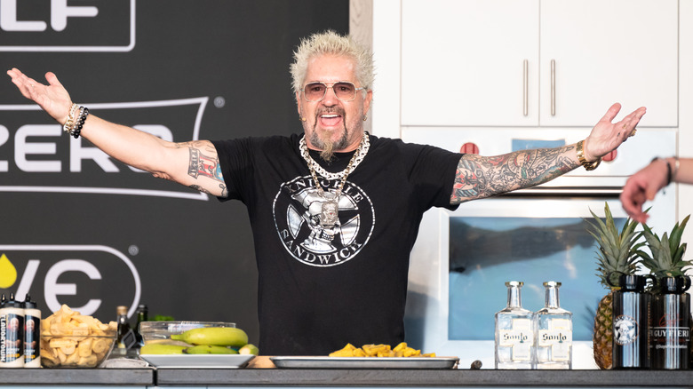 Guy Fieri enthusiastically greeting the audience at a cooking demonstration