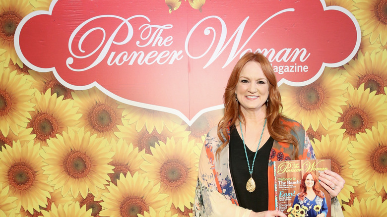 Ree Drummond posing with "Pioneer Woman" Magazine against a wall with her logo at an event