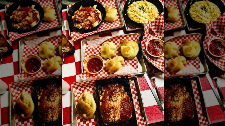 overheat shot of a table filled with Italian dishes like lasagna, pasta and red sauce, and garlic knots