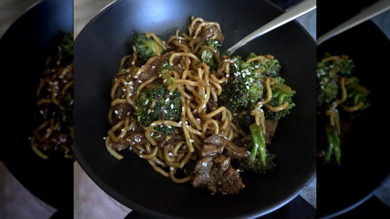 A black bowl contains Kirkland Signature Beef and Broccoli with Noodles.