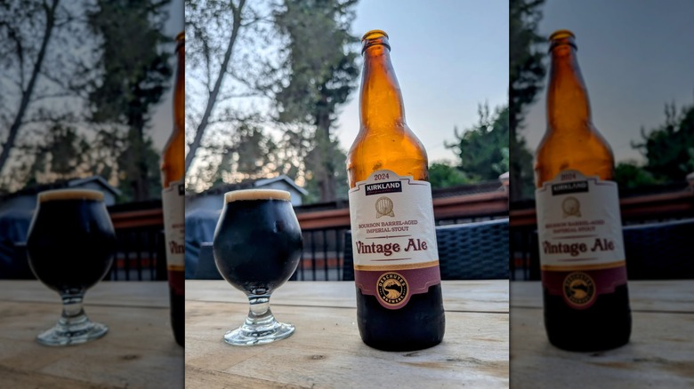 A bottle and glass of Kirkland Signature Vintage Ale sit on a wooden table.