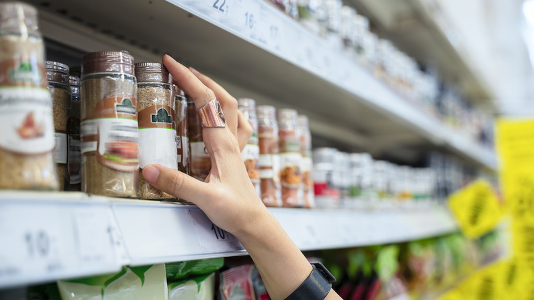 hand grabbing spice bottle off a store shelf
