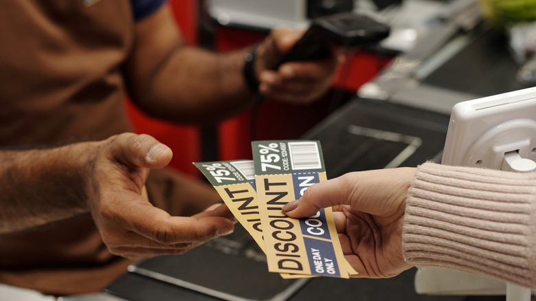 close up of customer giving coupons to a clerk