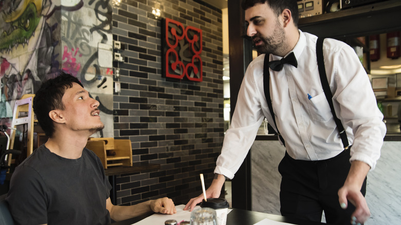 Waiter talking to a customer sat at a table