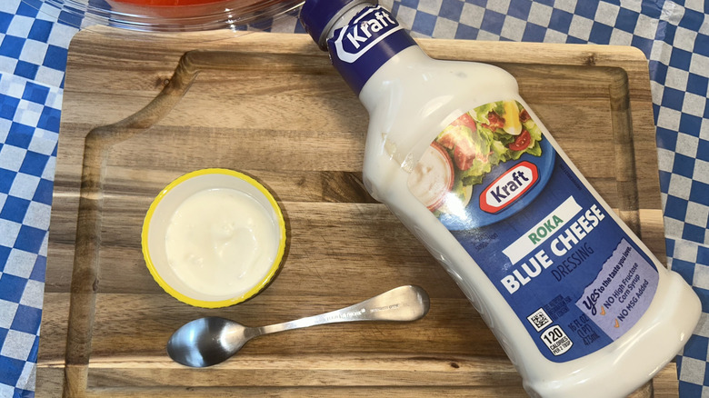 Bottle of Kraft blue cheese dressing with small ramekin of dressing and a spoon