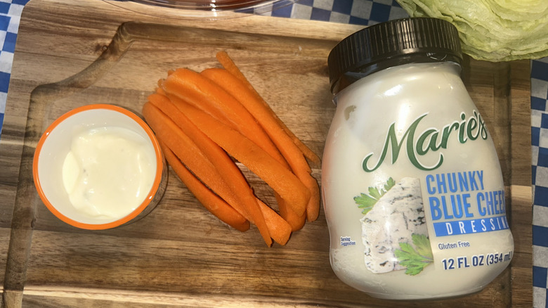 Jar of Marie's blue cheese dressing with carrots and a ramekin, lettuce in the background