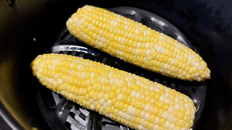 Two corn cobs in an air fryer